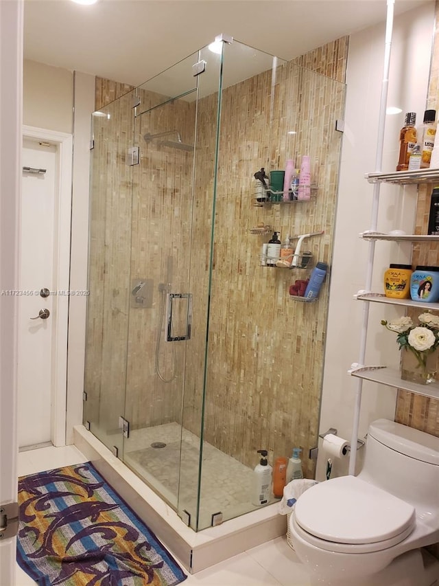 bathroom featuring toilet, tile patterned flooring, and a shower with shower door