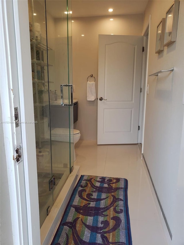 bathroom with an enclosed shower, toilet, and tile patterned flooring