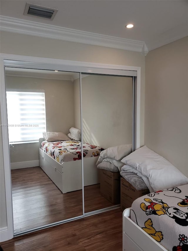 bedroom featuring a closet, ornamental molding, and hardwood / wood-style flooring