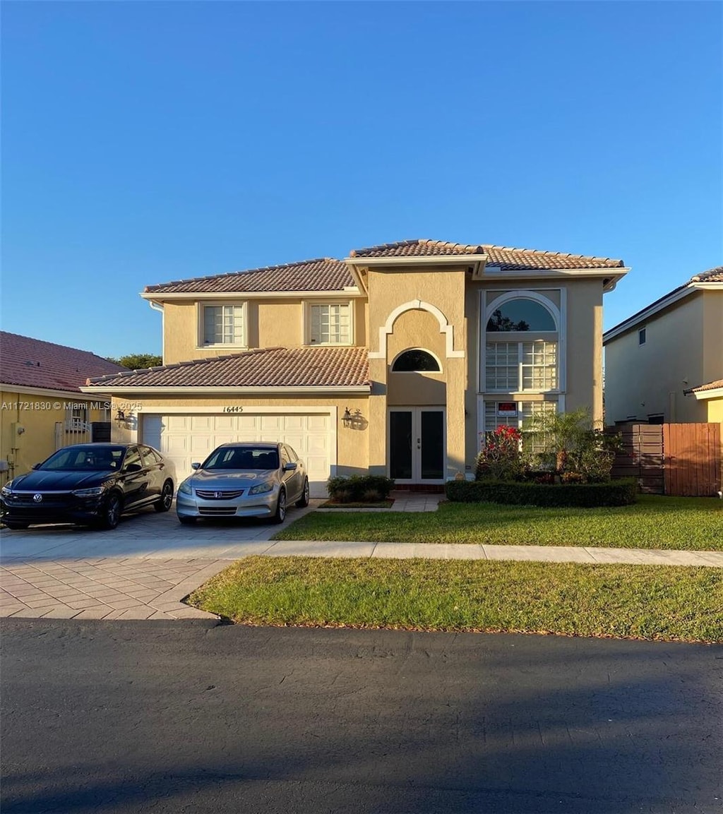 mediterranean / spanish-style home with a front lawn, french doors, and a garage