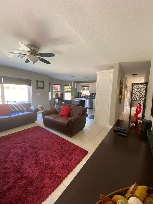 living room featuring ceiling fan, light tile patterned floors, and a textured ceiling