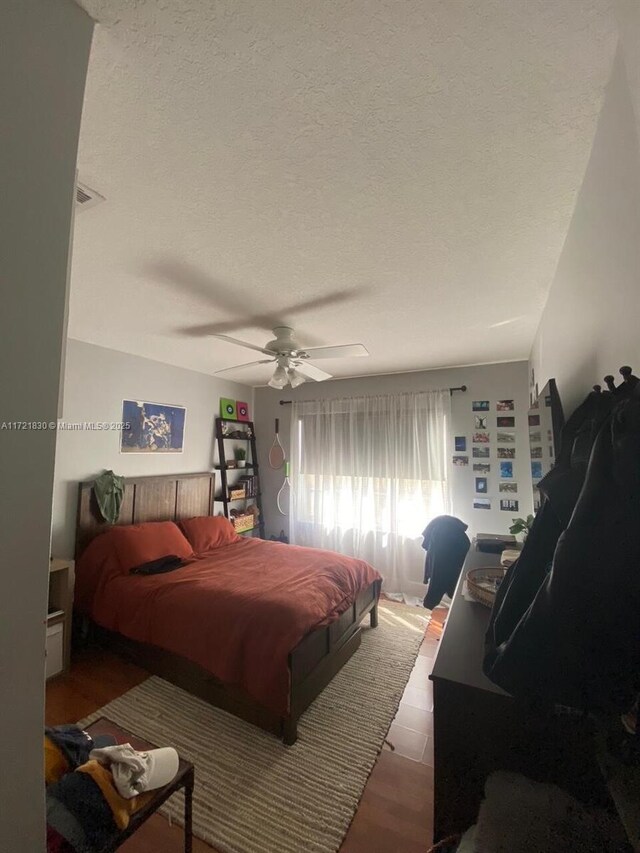 bedroom featuring ceiling fan, a textured ceiling, and light wood-type flooring