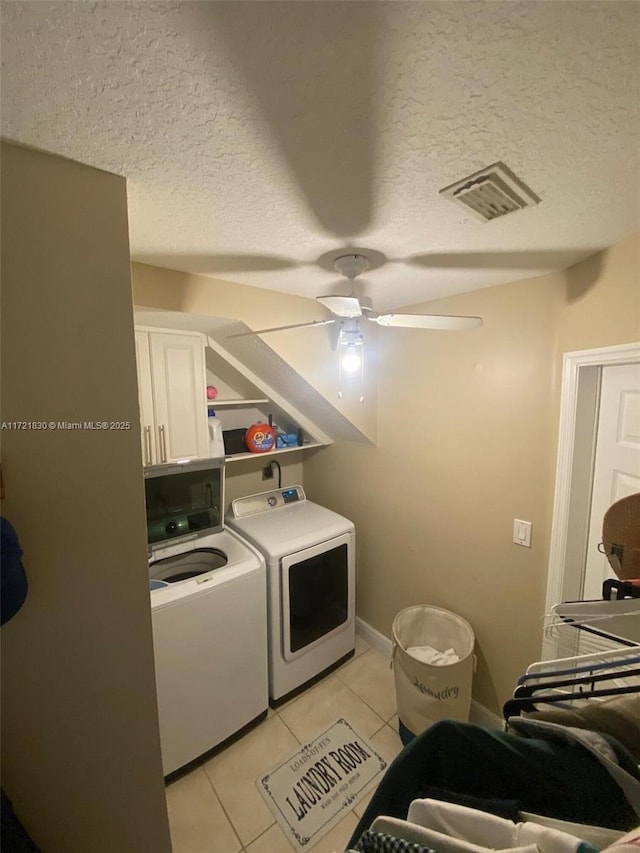 washroom featuring cabinets, light tile patterned floors, independent washer and dryer, and a textured ceiling