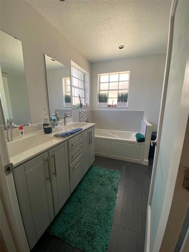 bathroom featuring hardwood / wood-style flooring, vanity, a textured ceiling, and a bathtub