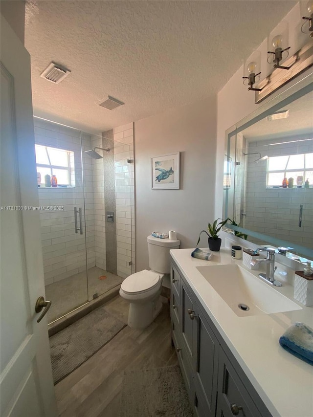 bathroom featuring walk in shower, vanity, toilet, and a wealth of natural light