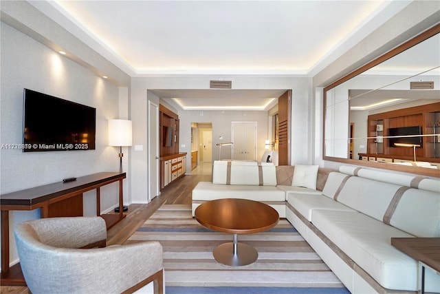 living room featuring wood-type flooring and a tray ceiling