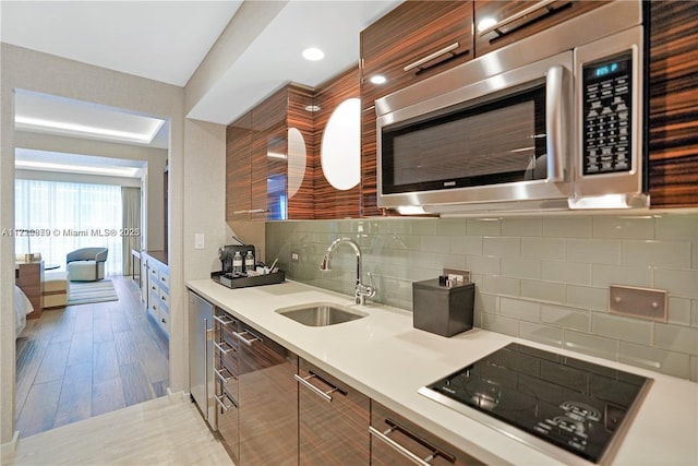 kitchen with black electric stovetop, backsplash, and sink