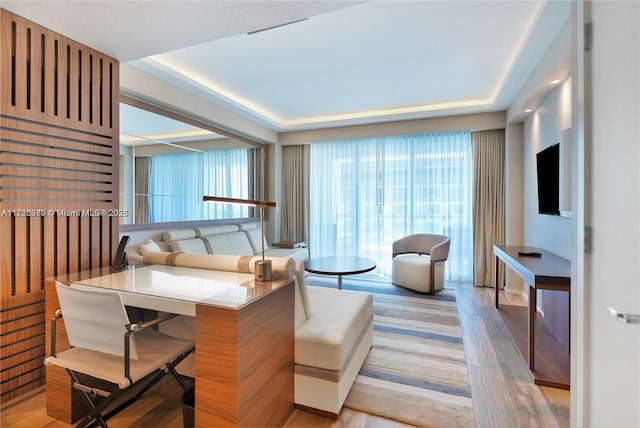 living room featuring light wood-type flooring and a tray ceiling