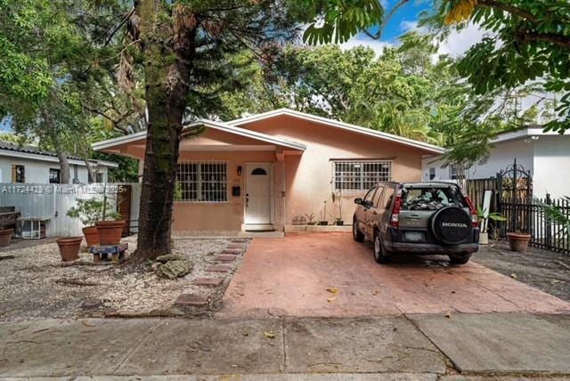 bungalow-style home with fence and stucco siding