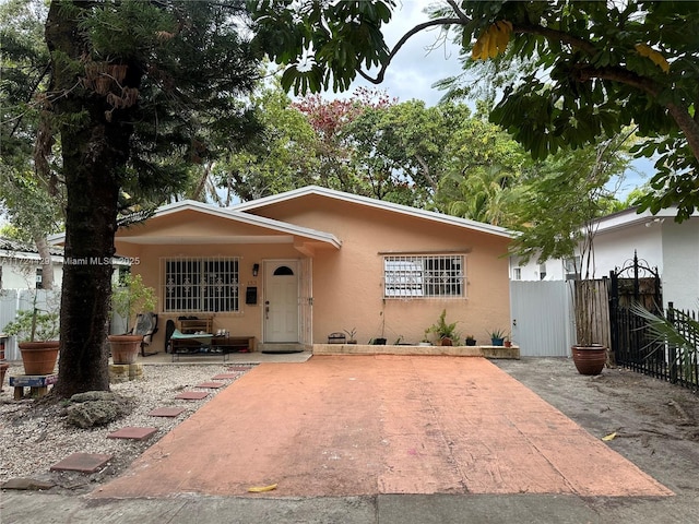 view of front of property with a gate, fence, stucco siding, and a patio area