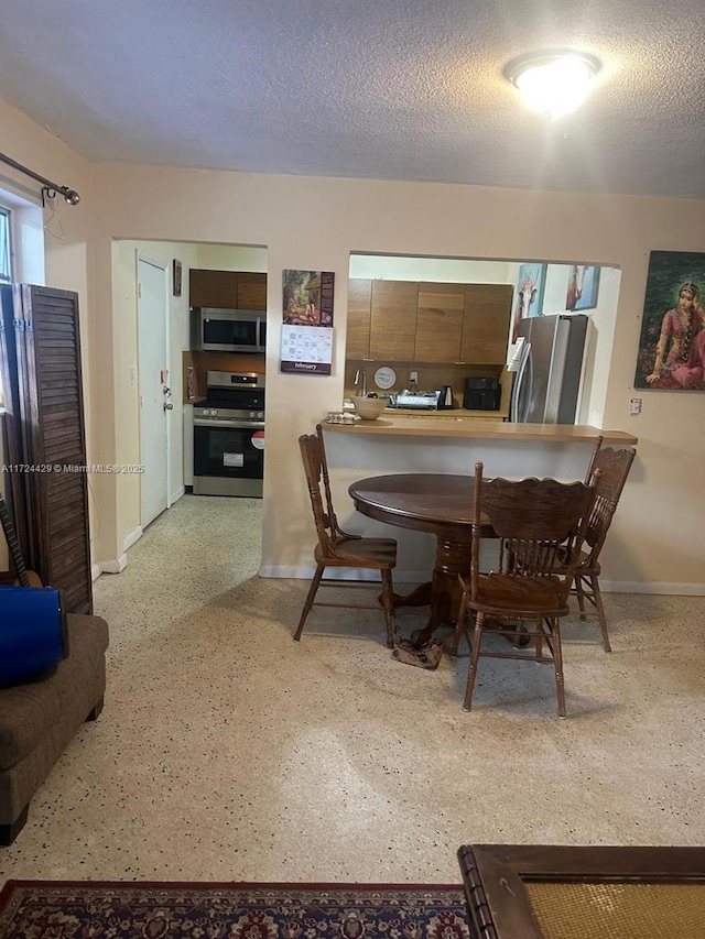dining area with a textured ceiling and baseboards