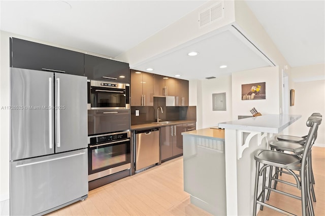 kitchen featuring stainless steel appliances, a kitchen island, a kitchen breakfast bar, electric panel, and sink