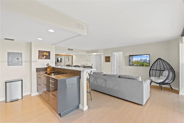 kitchen with a kitchen bar, light hardwood / wood-style floors, black electric cooktop, and kitchen peninsula