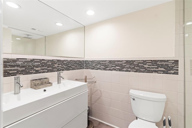 bathroom with toilet, tile walls, and vanity