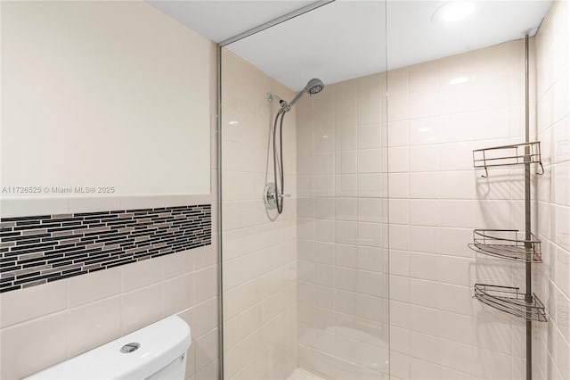 bathroom with tile walls, toilet, and tiled shower