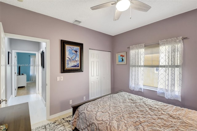 tiled bedroom featuring ceiling fan, a closet, and a textured ceiling