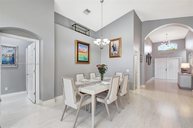 dining area with light hardwood / wood-style flooring, a chandelier, and a high ceiling