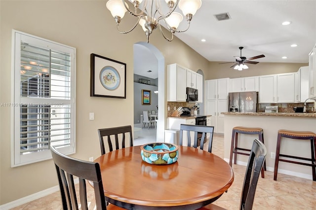 dining area with lofted ceiling, ceiling fan with notable chandelier, and light tile patterned flooring