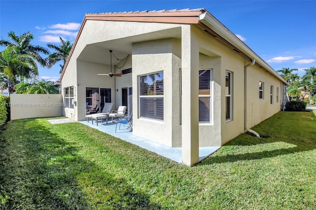 rear view of property with a yard, ceiling fan, and a patio area