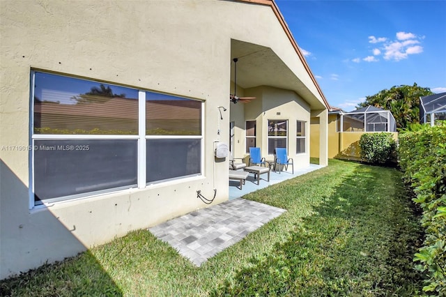 back of property with a patio, glass enclosure, and a lawn