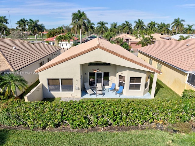 rear view of property featuring ceiling fan and a patio area