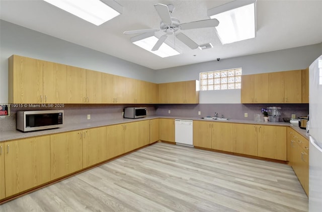 kitchen featuring white dishwasher, light brown cabinetry, tasteful backsplash, and sink