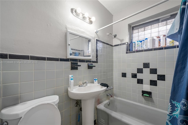 full bathroom featuring toilet, sink, tile walls, and shower / tub combo with curtain