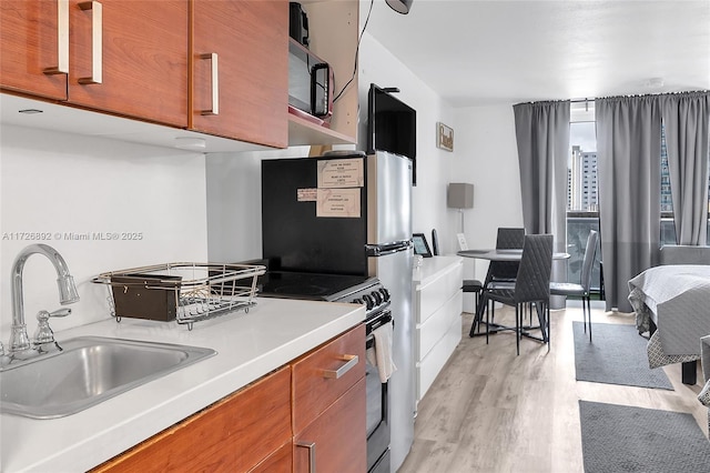 kitchen featuring stainless steel electric range oven, sink, and light hardwood / wood-style floors