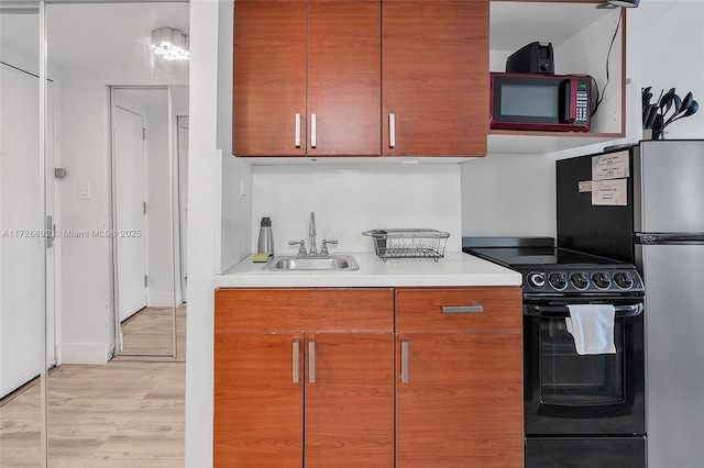 kitchen featuring black electric range oven, light hardwood / wood-style flooring, and sink