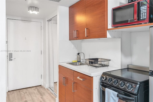 kitchen with sink, range with electric stovetop, and light wood-type flooring