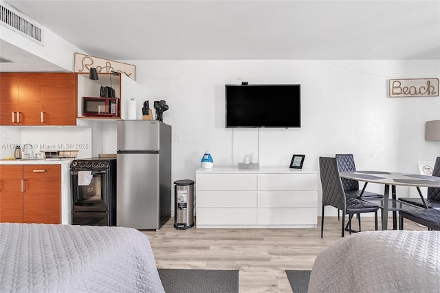 bedroom featuring stainless steel fridge and light wood-type flooring