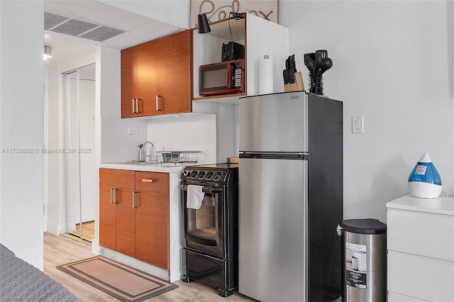 kitchen with black range with electric cooktop, light hardwood / wood-style floors, and stainless steel refrigerator