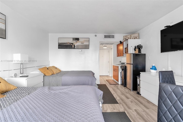 bedroom featuring stainless steel refrigerator and light hardwood / wood-style floors