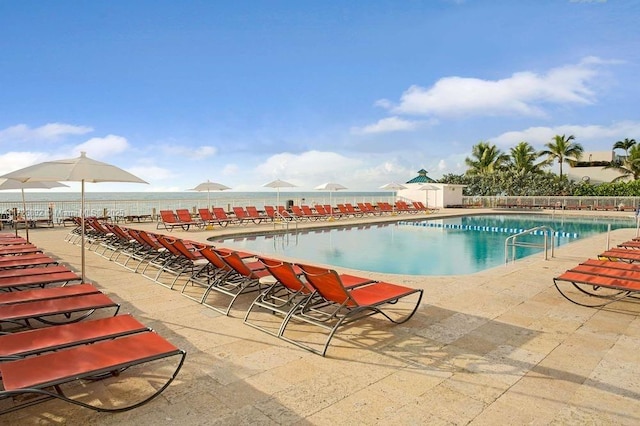 view of swimming pool with a water view and a patio area