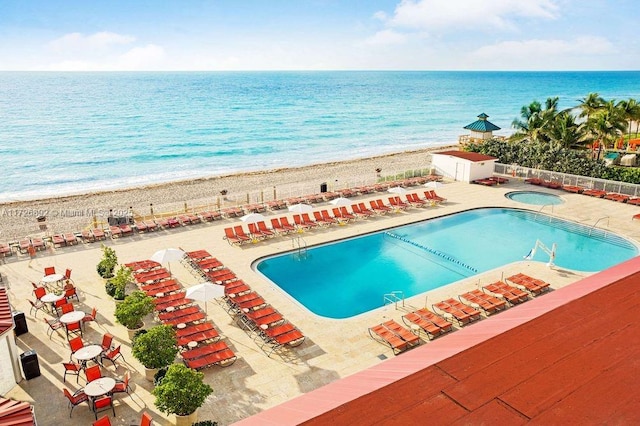 view of swimming pool featuring a patio, a beach view, and a water view