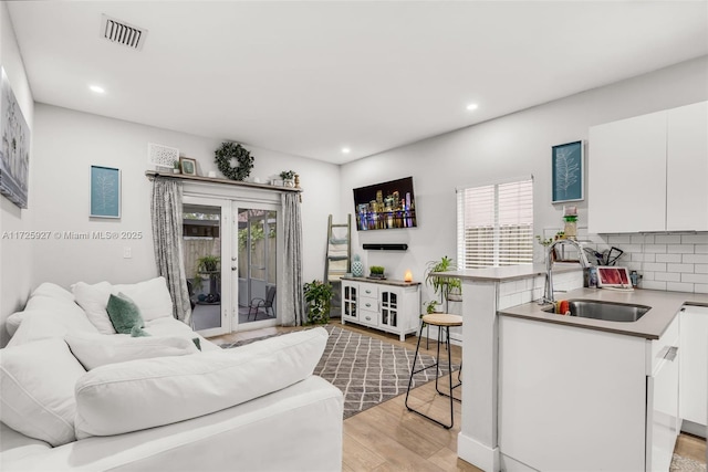 living room featuring sink, light hardwood / wood-style flooring, and french doors