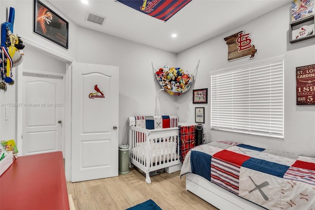 bedroom featuring a crib and hardwood / wood-style flooring