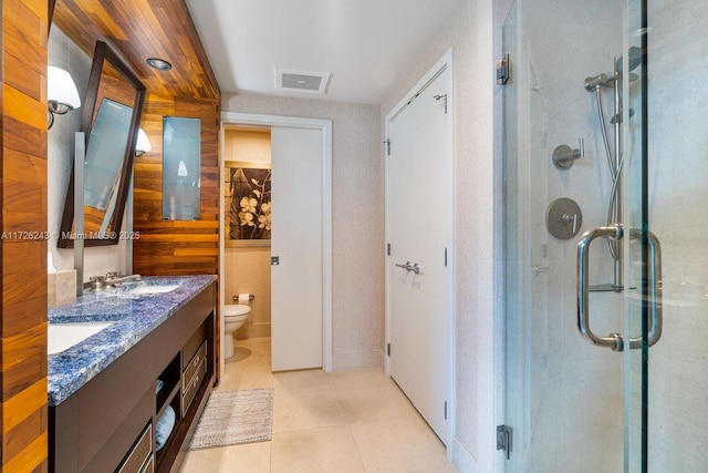 bathroom featuring toilet, vanity, an enclosed shower, and tile patterned floors