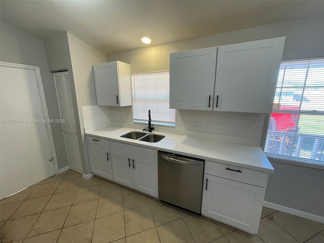 kitchen featuring stainless steel dishwasher, sink, white cabinetry, and light tile patterned flooring