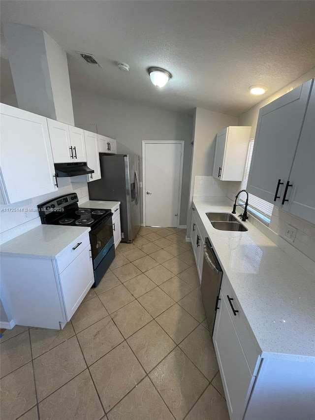 kitchen with sink, light tile patterned floors, appliances with stainless steel finishes, a textured ceiling, and white cabinets