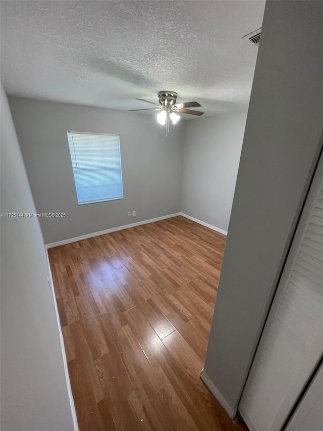 empty room with ceiling fan, hardwood / wood-style floors, and a textured ceiling