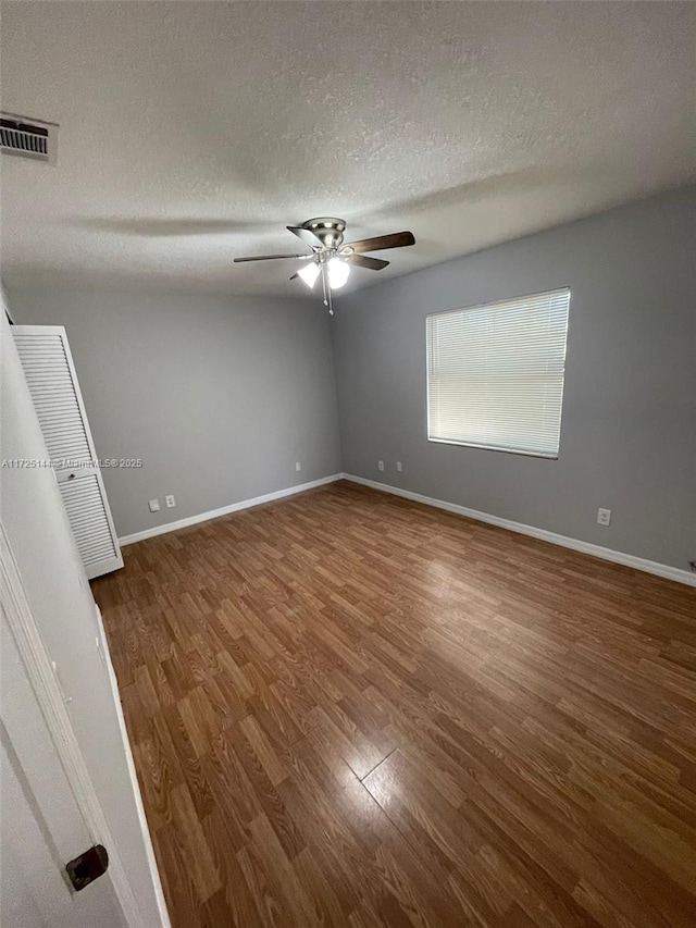 empty room featuring a textured ceiling, ceiling fan, and dark hardwood / wood-style floors