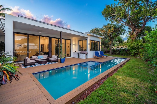 back house at dusk featuring a pool side deck and an outdoor hangout area