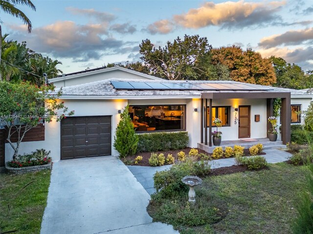 view of front of home featuring a lawn, solar panels, a porch, and a garage