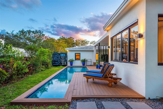 pool at dusk featuring a deck