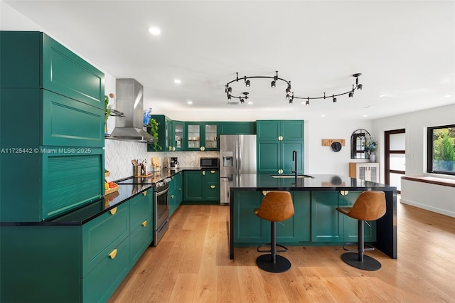 kitchen with a kitchen bar, stainless steel appliances, sink, ventilation hood, and green cabinets