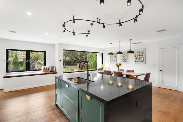 kitchen with an island with sink, plenty of natural light, sink, and hanging light fixtures