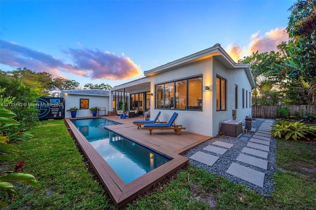 back house at dusk with a pool side deck