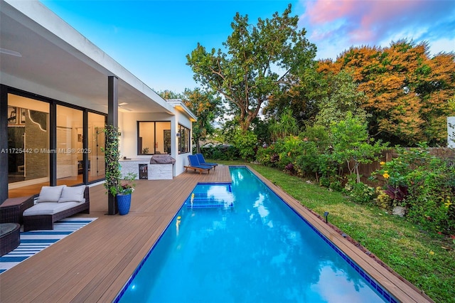 pool at dusk featuring a deck and outdoor lounge area