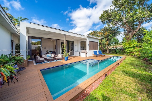 view of pool featuring a deck, outdoor lounge area, and a lawn